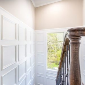 Staircase with white panelled walls.